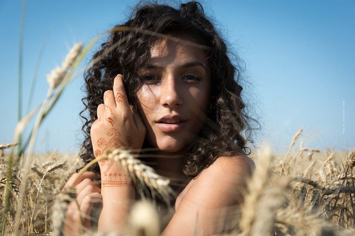 haare-schwarz-frau-locken-feld-himmel-blau-beige-tatto
