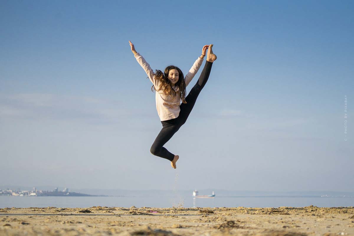 tanzworkout-springen-madchen-lachen-meer-sand-sport-training-sportkleidung